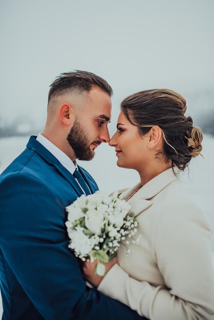 Braut und Bräutigam unter schneebedeckten Bergen Sie stehen und umarmen Winterhochzeit im Freien Nahaufnahme