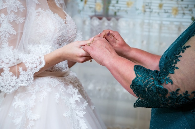 Braut und Mutter halten sich am Hochzeitstag an den Händen