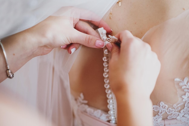 Brautjungfer kleidet Braut auf Hochzeit, Nahaufnahme