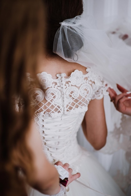 Brautjungfern helfen der Braut beim Anziehen des Kleides