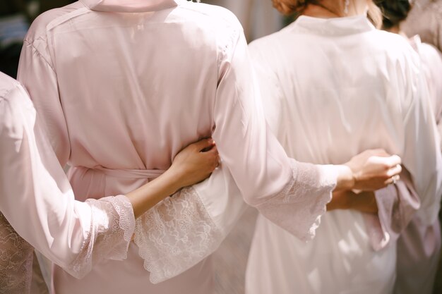 Brautjungfern in Roben umarmen sich in der Rückansicht