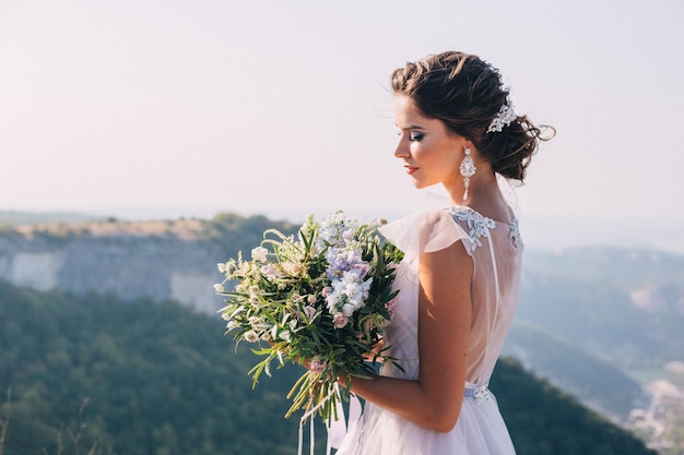 Brautporträt mit herrlichem Blumenstrauß auf einem Bergblick