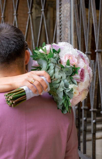 Brautstrauß aus rosa, weißen und lila Rosen in der Hand der Braut.