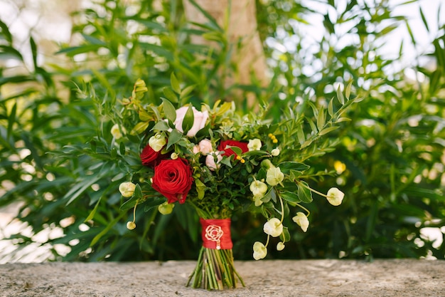 Brautstrauß aus roten und rosa Rosen Buchsbaumzweigen, die keine Knospen aus weißen Blüten und Rot blühen