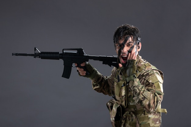 Bravo soldado de frente lutando camuflado com metralhadora na parede escura