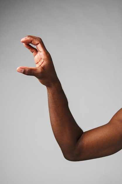 El brazo de un hombre africano revela la fuerza muscular en un fondo gris