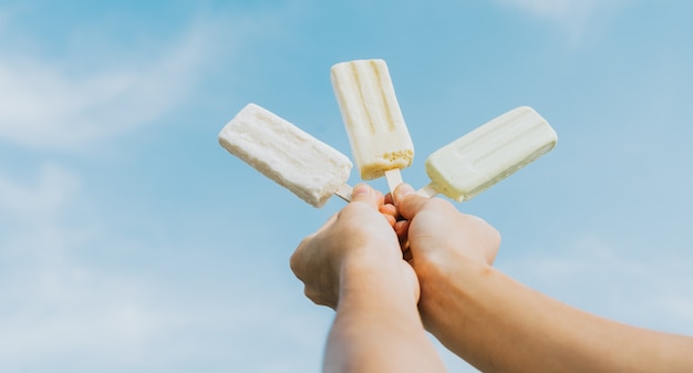 Brazo de hombre asiático sosteniendo helado derritiéndose en el cielo