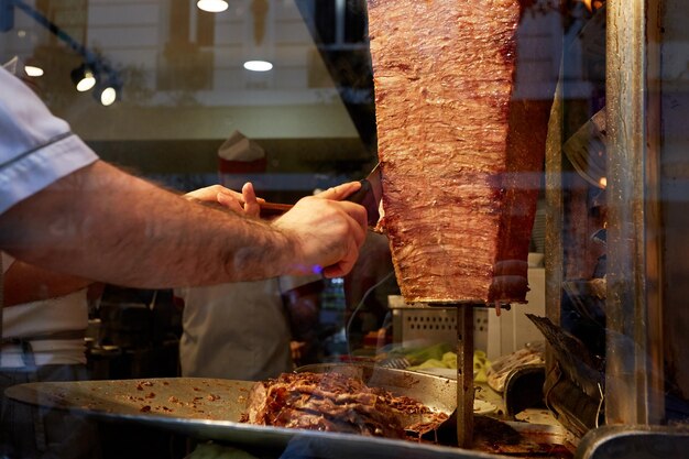 Un brazo moviéndose para cortar la carne de kebab.