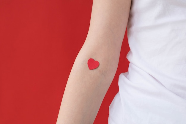 Brazo de una niña con un corazón rojo