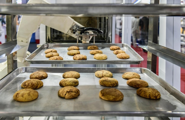 Brazo robótico preparando galletas para el horno en la fábrica de la línea de producción