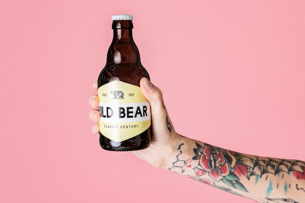 Brazo tatuado sosteniendo una botella de vidrio marrón