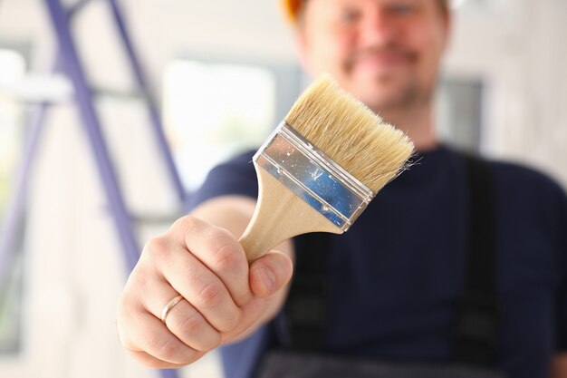 Brazo de trabajador sonriente sostener cepillo closeup