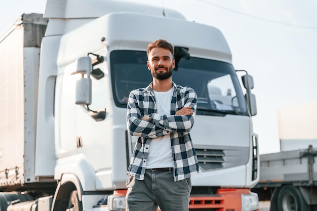 Con los brazos cruzados, el joven camionero está con su vehículo durante el día