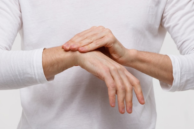 Brazos de hombre sosteniendo su muñeca dolorosa, síndrome del túnel carpiano, artritis