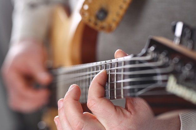 Brazos masculinos que tocan la guitarra eléctrica de forma clásica