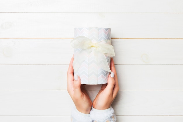 Brazos de mujer con caja de regalo con cinta de color