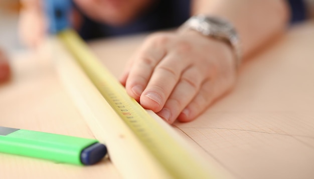 Brazos de trabajador midiendo barra de madera