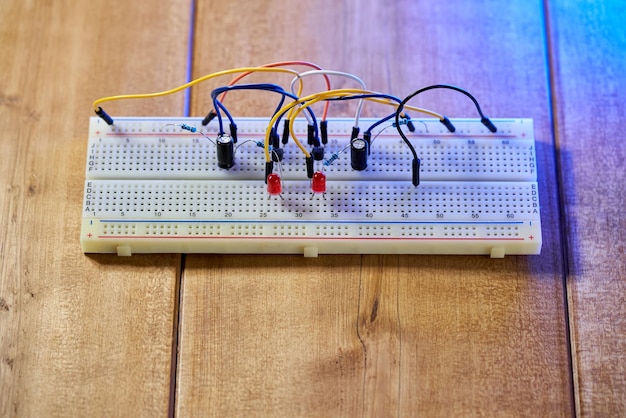 Breadboard com elementos elétricos, em uma mesa de madeira.