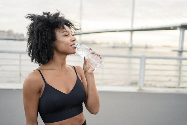 Break trinkt Wasser in Flaschen Eine Frau in Sportkleidung