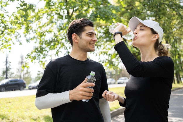 Break Trinkwasser in Flaschen Mann und Frau Training läuft im Park Ein junges Paar glücklich