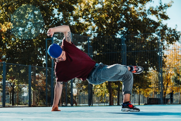 Breakdance des jungen Mannes am Basketballplatz