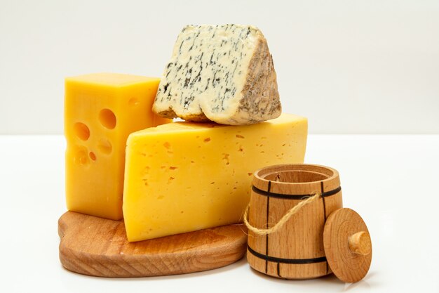 Breaks of fourme d'ambert, um queijo azul francês semiduro e queijo da polônia fazem sucesso em uma tábua de madeira com superfície branca