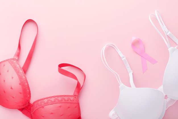 Breast Cancer Awareness Ribbon Weißer und roter BH mit rosa Schleifenband, das auf weiblichem BH auf Hintergründen liegt Brustkrebsbewusstsein und Oktober Rosa Tag Weltkrebstag Draufsicht Mock up