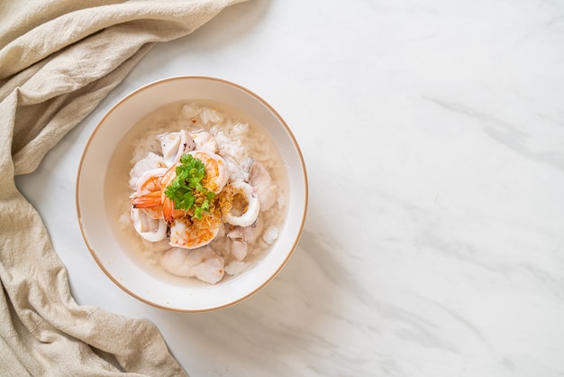 Brei oder gekochte Reissuppe mit Meeresfrüchten (Garnelen, Tintenfisch und Fisch) Schüssel