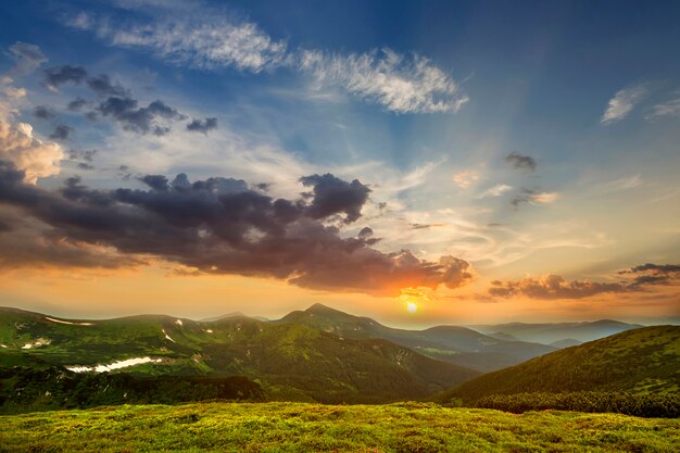 Breites Panorama von morgendlichem sonnengrünem Tal, mit Wald bedeckten Hügeln und fernen nebligen Bergen mit Schneeflecken unter bewölktem windigem Himmel. Schönheit der Natur, Tourismus und Reisekonzept.