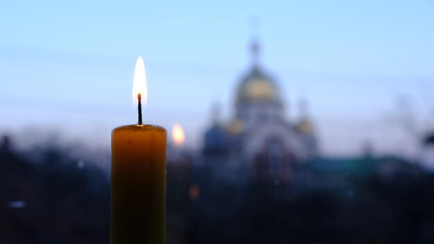 Brennende Kerze mit einer blured Kirche im Hintergrund mit den Buntglasfenstern Standort Ukraine