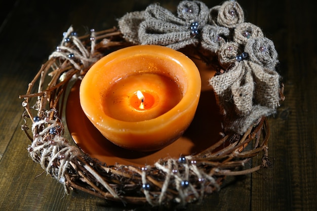 Brennende Kerze mit Weihnachtskranz auf Holzuntergrund