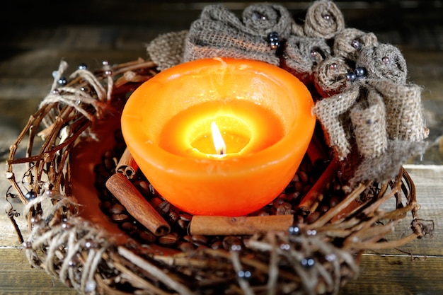 Brennende Kerze mit Weihnachtsschmuck auf farbigem Holzhintergrund