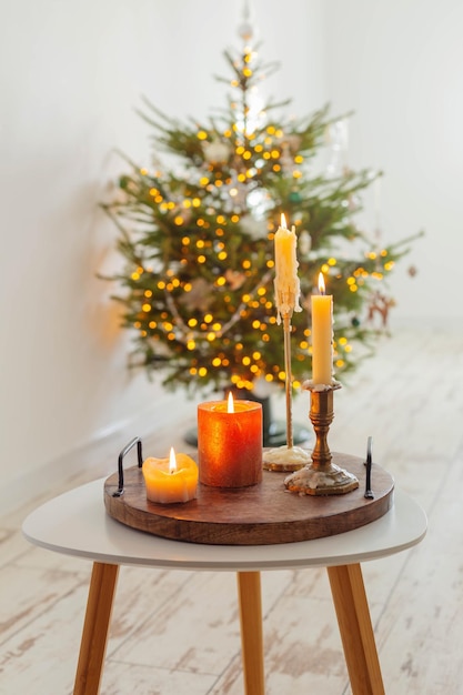 Brennende Kerzen auf dem Tisch im Hintergrund Weihnachtsbaum zu Hause