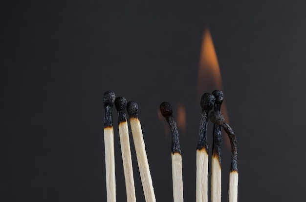 Brennende Streichhölzer mit orangefarbenen Flammen auf schwarzem Hintergrund