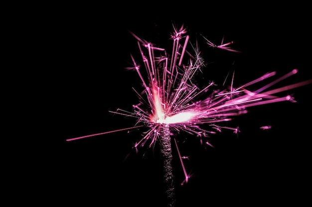 Brennende Wunderkerze in rosa und weißem Licht auf schwarzem Hintergrund Nahaufnahmefoto von Weihnachten und Neujahr Wunderkerze Kann wie ein Hintergrundbild oder eine Postkarte verwendet werden