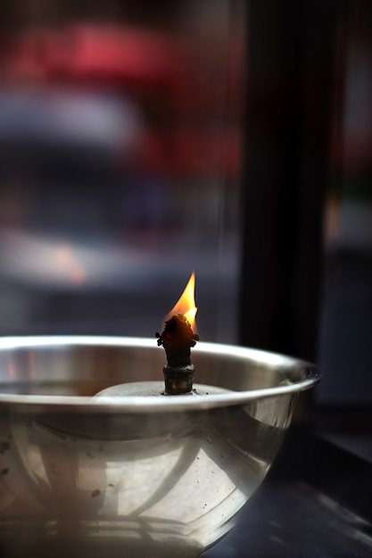 Brennendes und brennendes Kerzenfeuer, das auf Brennstoff in einem Buddhismustempel für das Beten und medi schwimmt