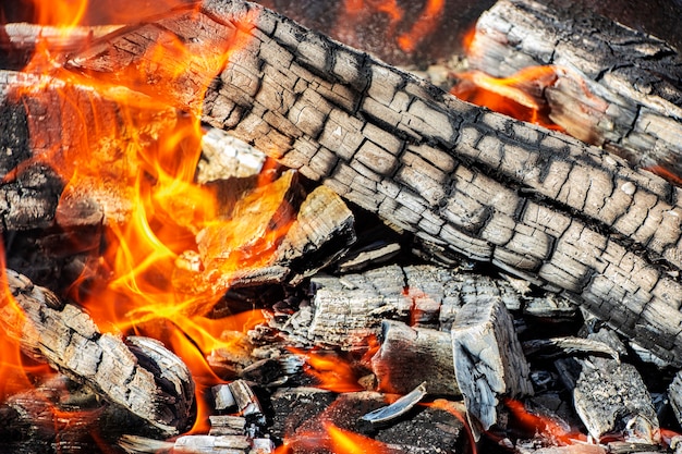 Brennholz und Kohlen im Grill verbrennen. Brennendes Feuer. Fleisch grillen. Kohlen zum Braten.