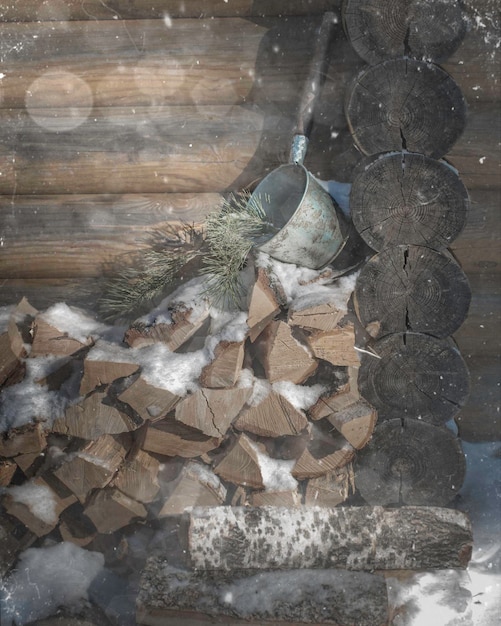 Brennholzstapel für Sauna mit Badezubehör auf altem Holzhüttenhintergrund.