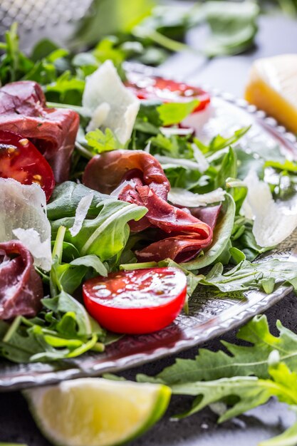 Bresaola de ternera seca. Ensalada bresaola rúcula espinacas tiernas tomates lima y queso parmesano.