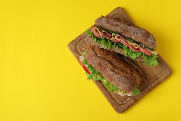 Brett mit Ciabatta-Sandwiches auf gelbem Hintergrund