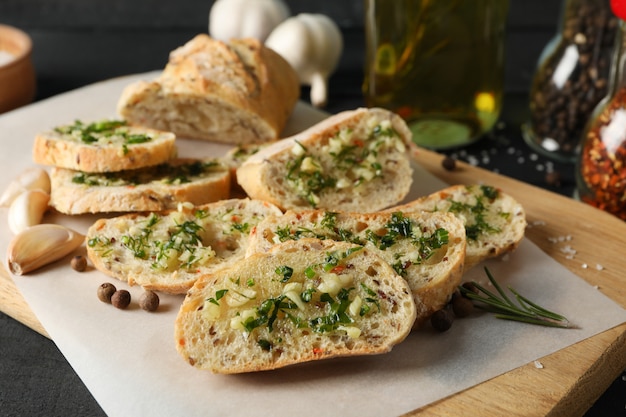 Brett mit geröstetem Knoblauchbrot und Gewürzen auf Holz