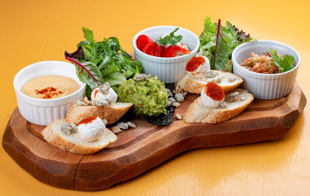 Brett mit leckeren Snacks Guacamole-Aubergine mit Dor-Blauschimmelkäse mit Paprika-Auberginen-Püree