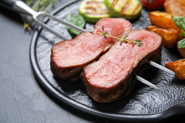 Brett mit Scheiben gegrilltem Fleisch auf schwarzer Tischnahaufnahme