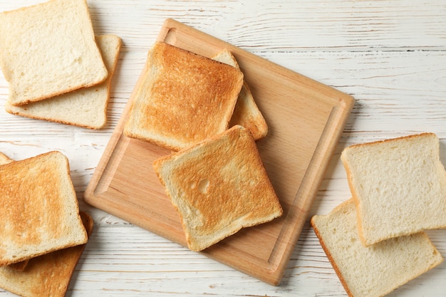 Brett mit Toast auf weißem hölzernem Hintergrund, Draufsicht