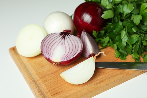 Brett mit Zwiebel, Petersilie und Messer auf weißem Hintergrund