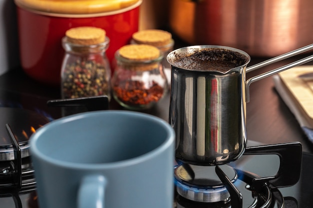 Brew café em um turco de aço em um fogão a gás