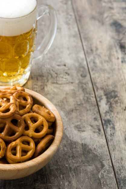 Brezeln in der Schüssel und im Bier auf Holztisch