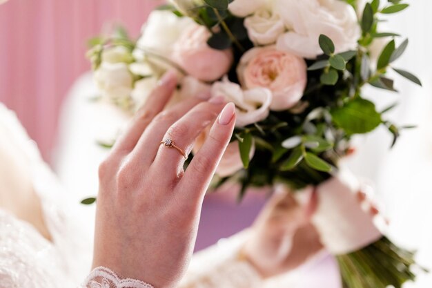 Bride39s Hand mit einem Ehering auf einem Hochzeitsblumenstrauß