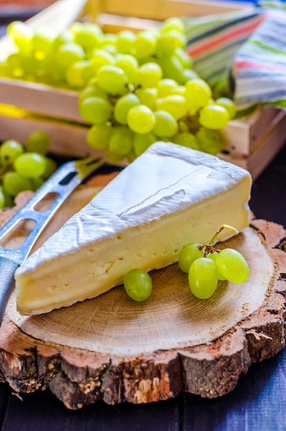 Brie-Käse und weiße frische Trauben auf einem Holzbrett