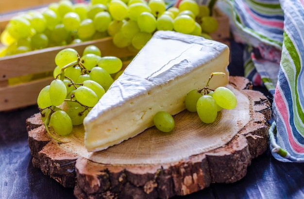 Brie-Käse und weiße frische Trauben auf einem Holzbrett